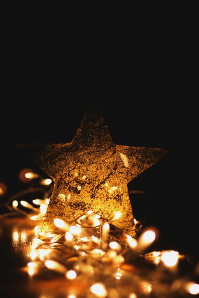 A shimmering golden star surrounded by warm Christmas string lights on a dark background. Perfect for holiday themes.